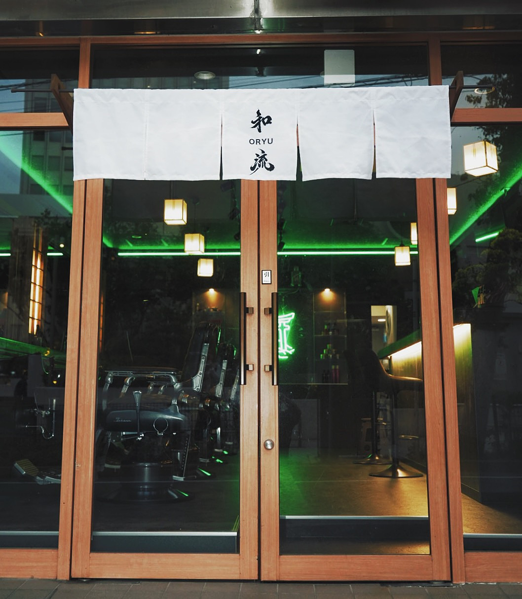 白い暖簾に「和流 ORYU」の文字、店内のグリーンネオンが灯る外観